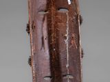 a brown wooden mask with holes on the side of it