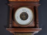 a clock on the wall that has a barometer on top of it