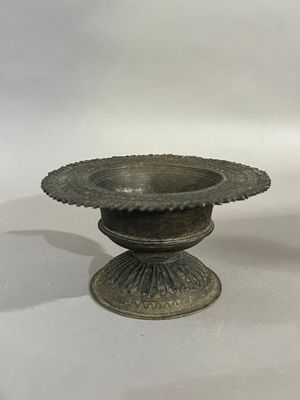 un petit bol en métal posé sur une table blanche