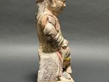 an old statue of a woman sitting on a rock with her hands in her pockets