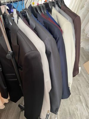 a lot of suits hanging on a rack in a room