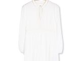 La chemise blanche est suspendue à un cintre accroché à un mur blanc.