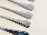 several spoons and forks are lined up on a white surface