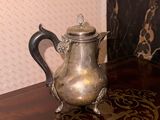 a silver tea pot sitting on a table in a room