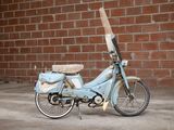 a small blue motorcycle parked in front of a brick wall