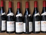 six bottles of red wine are lined up on a shelf