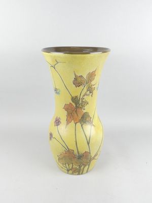 un vase jaune orné de fleurs sur fond blanc