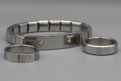 deux bracelets en acier inoxydable et une bague posés sur une surface blanche