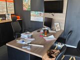 a desk with two chairs and a television in the corner