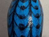 a blue and black vase sitting on a table