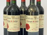 quatre bouteilles de vin rouge sont alignées sur une surface blanche