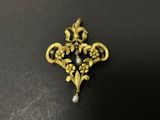 un gros plan sur une broche en or et perles