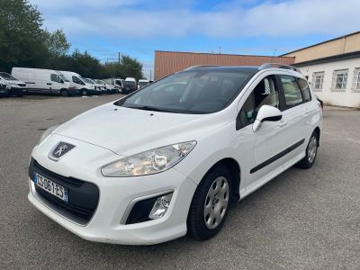 une voiture blanche garée dans un parking à côté d'un bâtiment