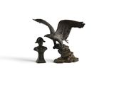 une image représentant une statue d'oiseau posée sur un rocher, à côté d'une statue de femme