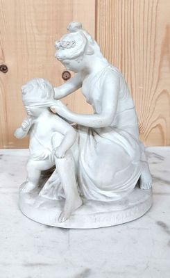 une statue représentant une femme et un enfant assis sur une table