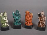 quatre figurines de couleurs, de formes et de tailles différentes, posées sur des socles noirs