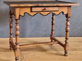 une vieille table en bois surmontée d'un tiroir, posée sur un parquet en bois massif
