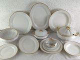 a lot of white and gold plates and bowls on a table