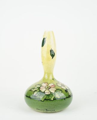 a green vase with flowers on it on a white surface