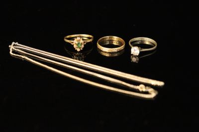 three gold rings and a pair of silver pins on a black surface
