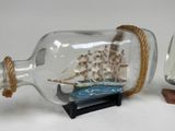 two miniature ships in a glass bottle on a table