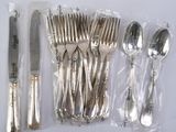 a lot of silverware on a white table