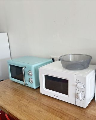trois micro-ondes posés sur une table, avec un saladier posé dessus