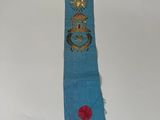 an image of a blue sash with a gold cross and a red rose on it