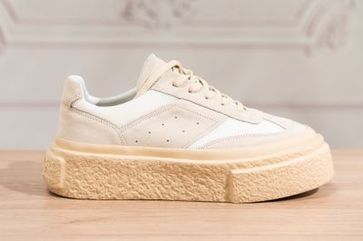 a close up of a pair of white sneakers on a wooden table