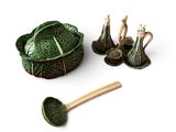 un chou vert et une cuillère en bois posés sur une surface blanche