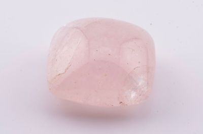 un gros plan d'un quartz rose posé sur une surface blanche