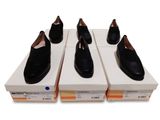 quatre paires de chaussures noires posées sur des cartons, sur une surface blanche