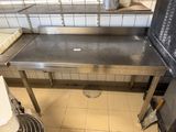a stainless steel table in a kitchen with a trash can