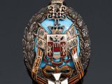 an image of a silver and blue broochle with a coat of arms on it