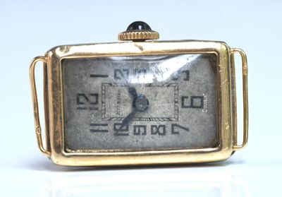 a small gold watch with a black face on a white surface