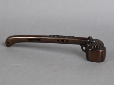 une vieille pipe munie d'un manche en métal, posée sur une table