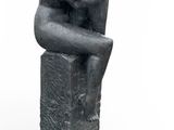 statue d'une femme assise sur un bloc, les mains posées sur les genoux