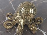 a gold figurine of an octopus on a marble table