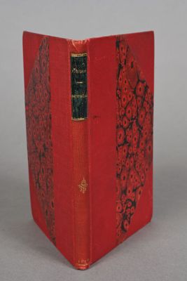 an old book with a red cover sitting on top of a table
