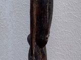 statue of a man standing on a wooden base in front of a white wall