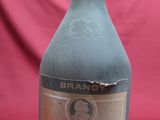 an old bottle of brandy sitting on a red cloth
