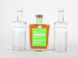 trois bouteilles d'alcool posées les unes à côté des autres sur une surface blanche