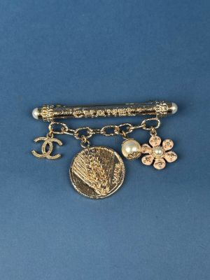 a gold brooch with charms on it on a blue surface