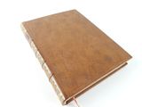 an old book with a brown cover sitting on top of a white surface