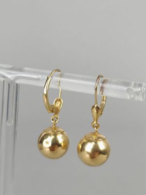 a pair of gold ball earrings on a clear plastic holder