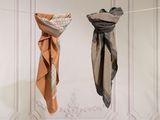 two scarfs hanging on a clothes line in front of a white wall