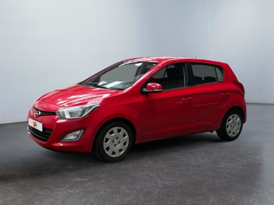 La voiture rouge est garée dans une pièce blanche au sol noir.