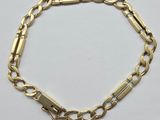 a close up of a gold chain bracelet on a white surface