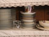 several plates and bowls are stacked on a shelf with a lace edge
