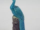 statue of a peacock sitting on a tree stump with a white background